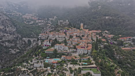 Eze-France-Aerial-v18-establishing-dolly-in-shot,-drone-flyover-hillside,-cliffside-medieval-village-and-exotic-botanical-garden---July-2021