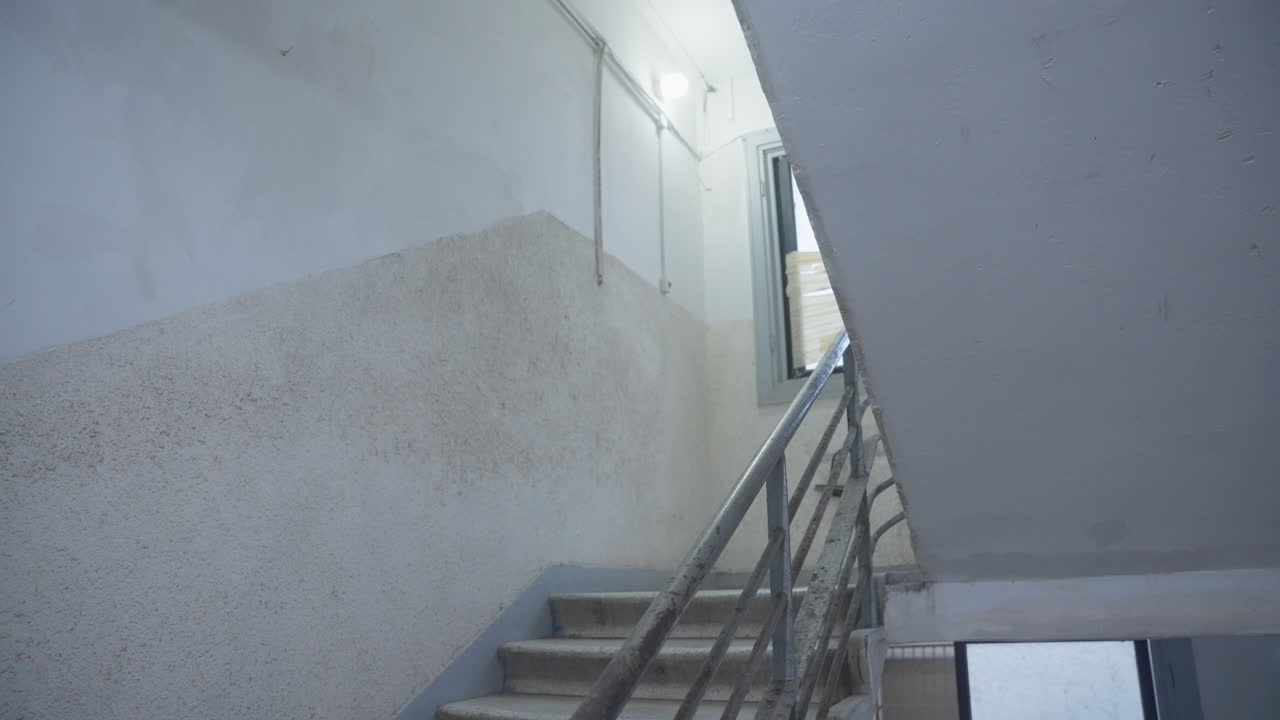 Man hurries down sketchy stairwell, holding a suitcase tightly, protecting something precious, classified files. Running away or being chased. Escape, secrecy, and underground dealings. spy or thief.