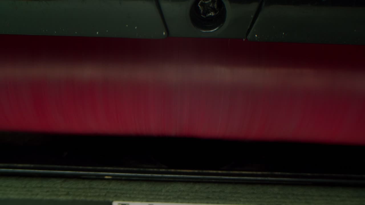 Close-up of a Vacuum Cleaner's Rotating Red Brush Cleaning Carpet