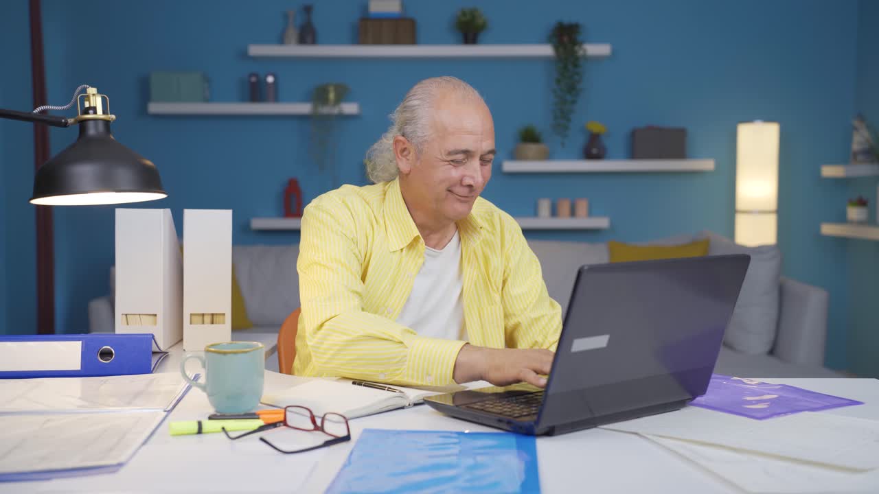 Home office worker old man smiles at camera.