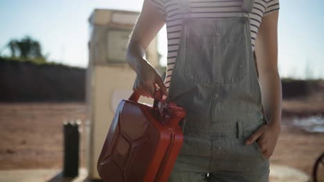 midsection of caucasian woman holding jerrycan at petrol station