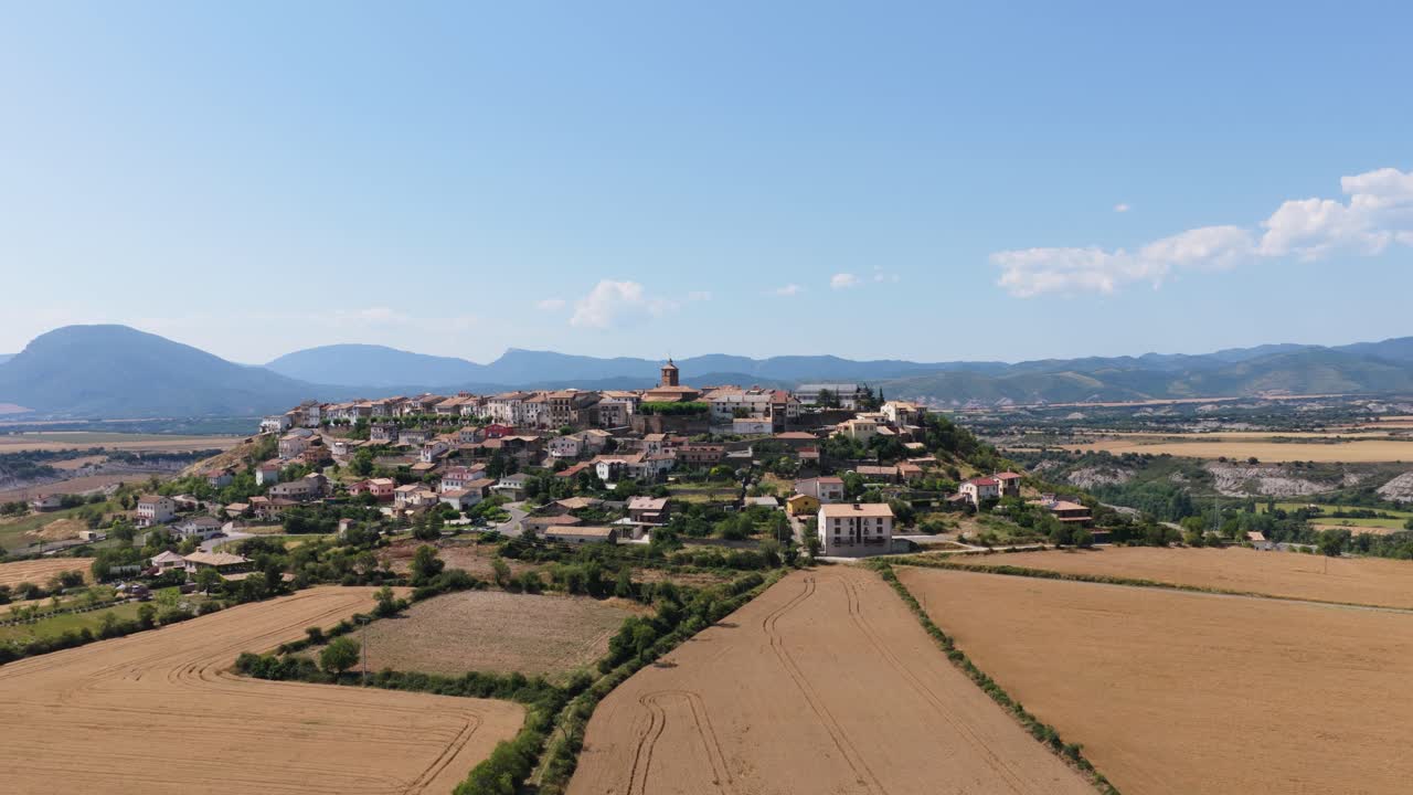 Vista aerea di un borgo storico in cima a una collina circondato da campi dorati
