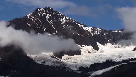 pequeñas nubes bajas alrededor de la montaña cubierta de nieve y el glaciar en la bahía del glaciar, alaska