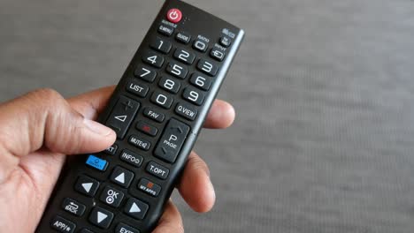 primer plano de un hombre con la mano sujetando el control remoto de la televisión