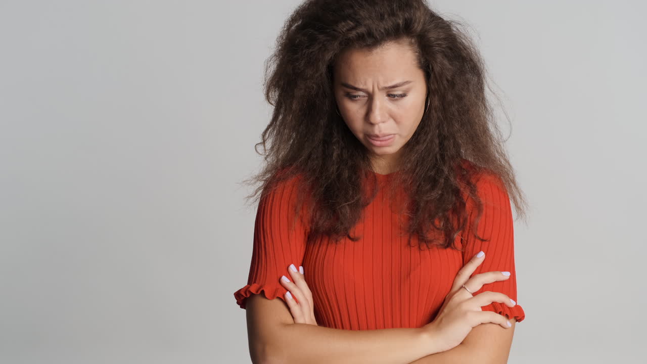 Caucasian curly haired woman looking worried to the camera.