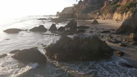 Aerial-view-of-rocks,-waves-and-people-walking-at-El-Matador-Beach-in-Malibu-California