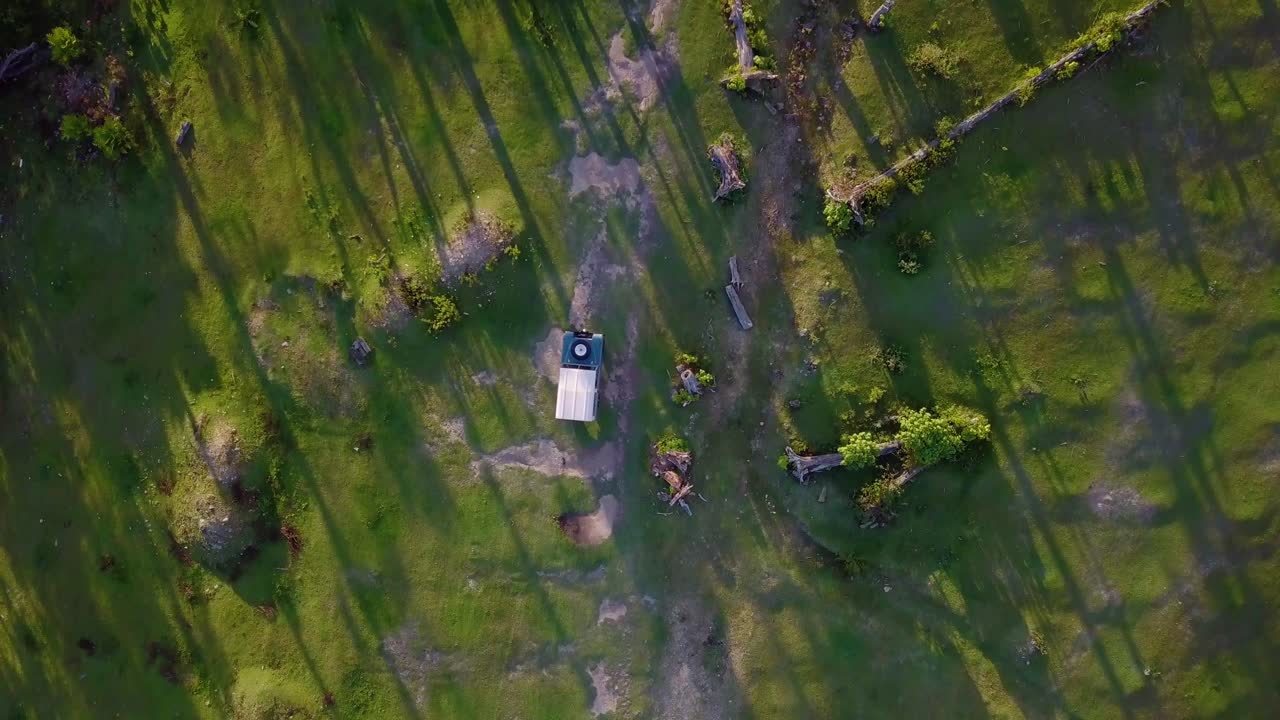 Aerial view above a 4x4 truck driving on a forest dirt road, in Cerro El Volcan, El Hatillo, Venezuela - top down, drone shot