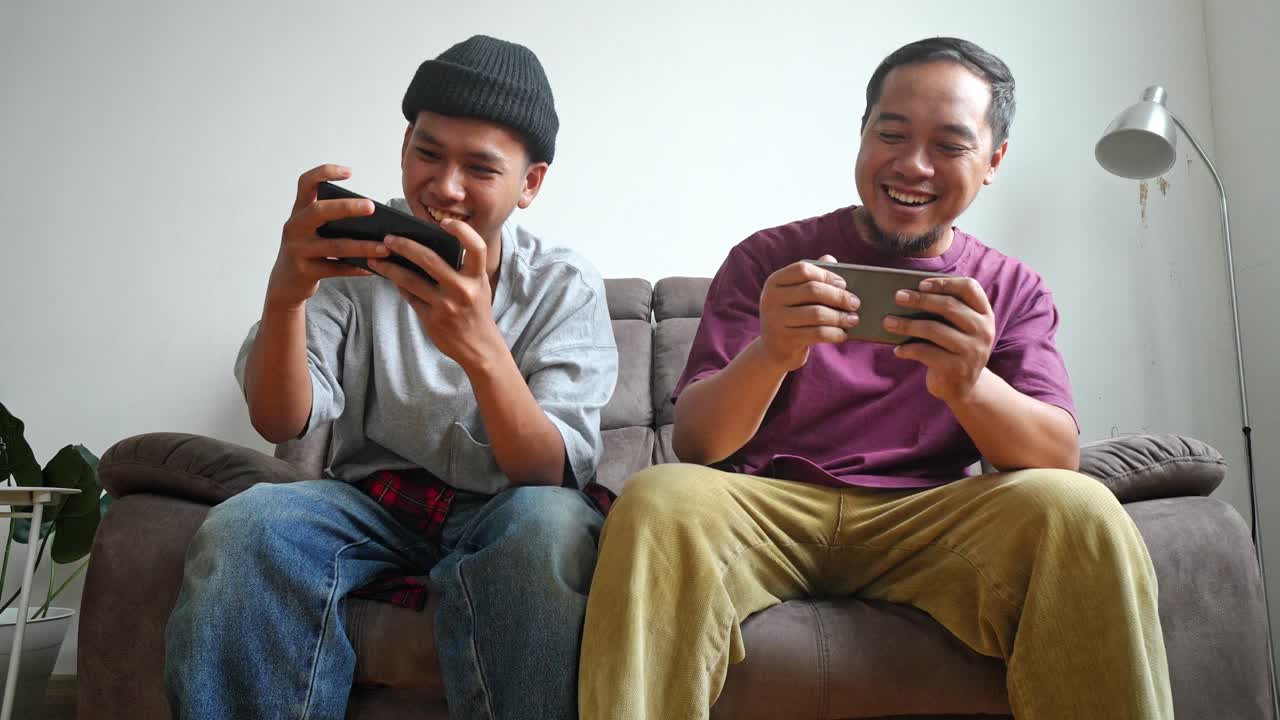 Two Men Playing Mobile Games on a Couch