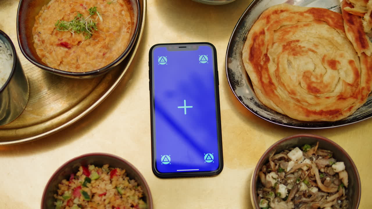 Table with Indian/Pakistani food and a smartphone