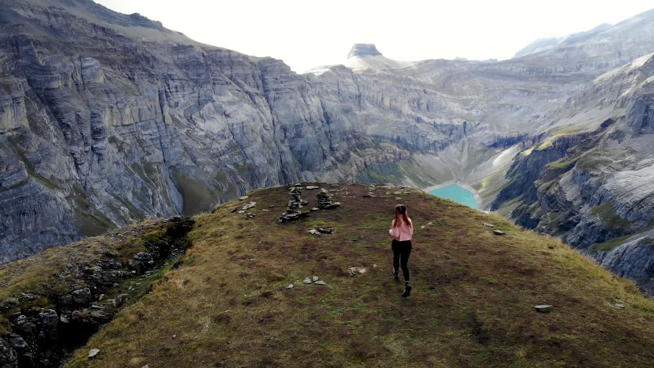 un excursionista corriendo hacia un mirador sobre el lago limernsee en glarus, suiza, cuyas aguas color turquesa están rodeadas de altos picos y acantilados de los alpes suizos
