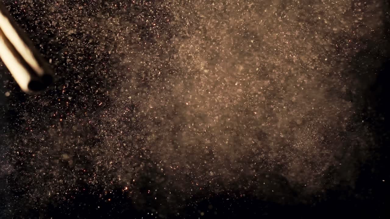 Top-down super slow motion shot of cinnamon sticks as spice powder bursts toward the camera. Dark background and cinematic lighting enhance texture and dramatic movement.