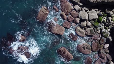 Concept-aerial-spins-and-ascends-from-waves-on-rocky-coast-shoreline