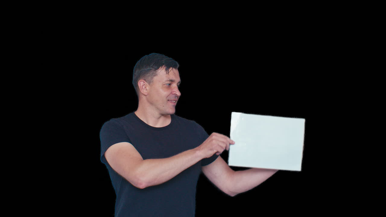 A male model man poses with white blank piece of sheet board and points at it on black chromakey transparent removed no background