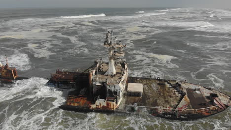 aerial rotation around remains of shipwreck - crashing waves