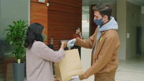 Courier-in-Mask-and-Gloves-Delivering-Order-to-Businesswoman