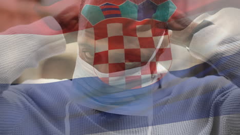 animation of flag of croatia waving over man wearing face mask during covid 19 pandemic