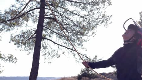 Woman-worker-smiles-because-not-able-to-unhook-a-rope-from-a-tree-while-gardening