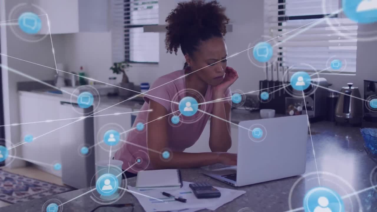 Animation of network of connections with icons over biracial businesswoman using laptop