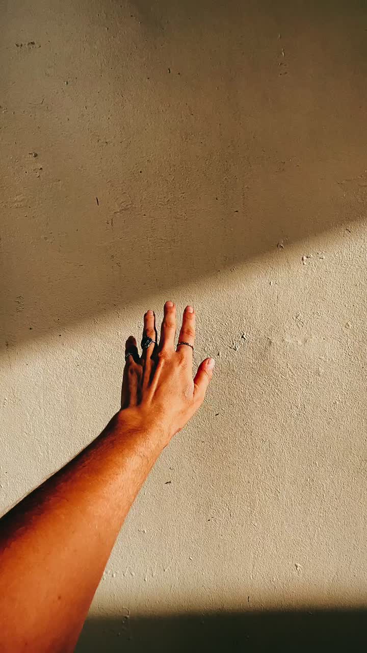 la mano extendiéndose contra una pared beige texturizada