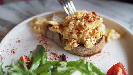 huevos revueltos en tostadas con una ensalada