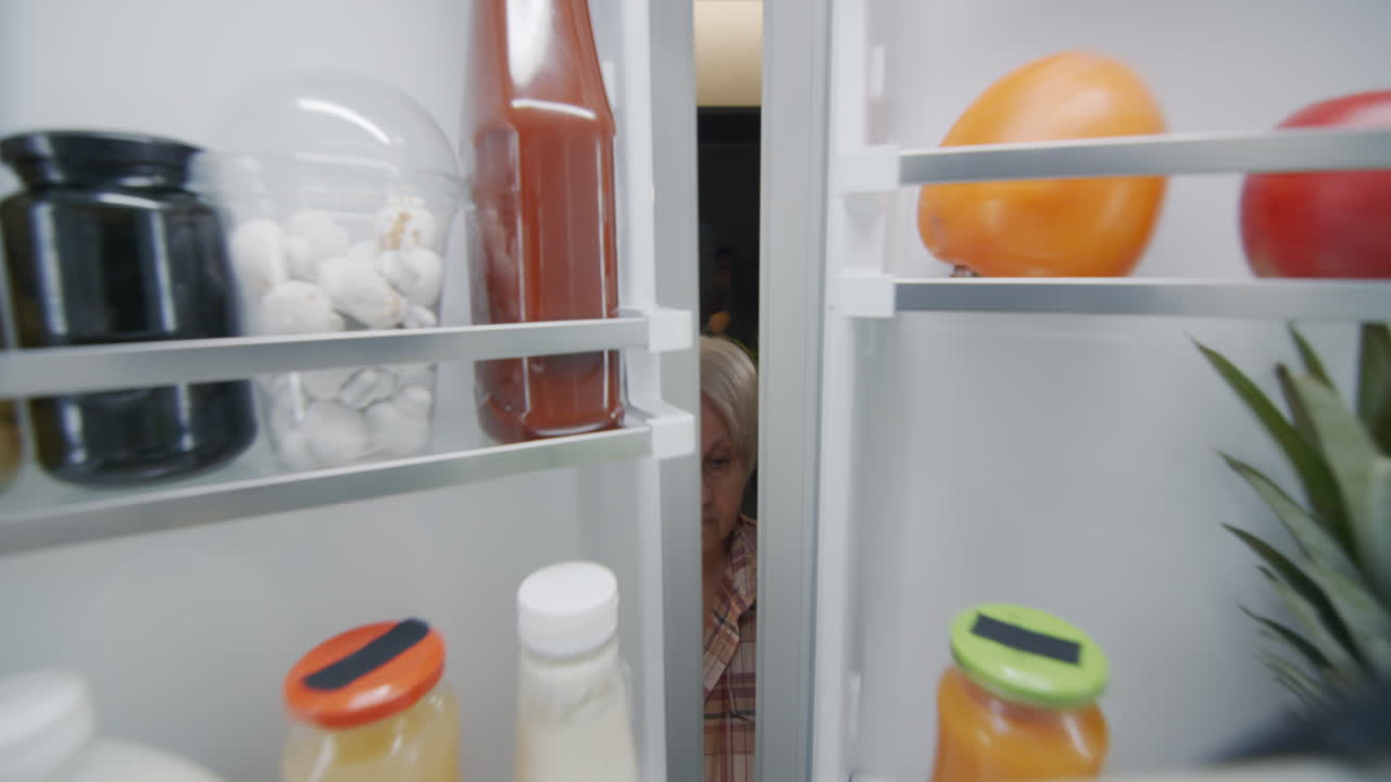 una mujer mayor poniendo una botella de leche en el refrigerador