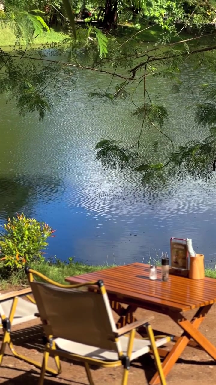 Tavolo e sedie da campeggio vuoti vicino a un lago calmo