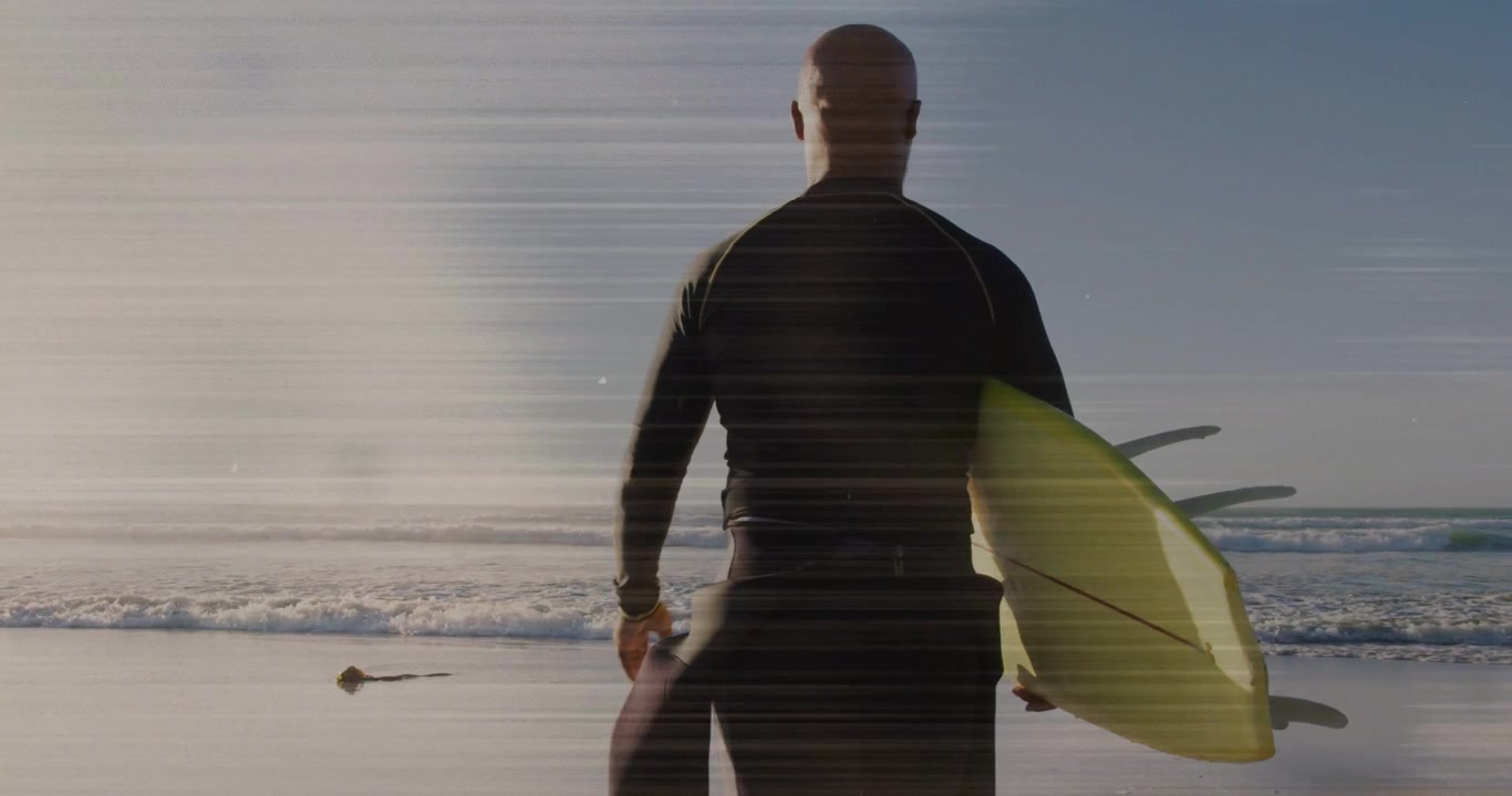 Surfista uomo che cammina verso l'acqua, spostando la tavola gialla con sovrapposizione di linee di scansione, preparandosi a fare surf.
