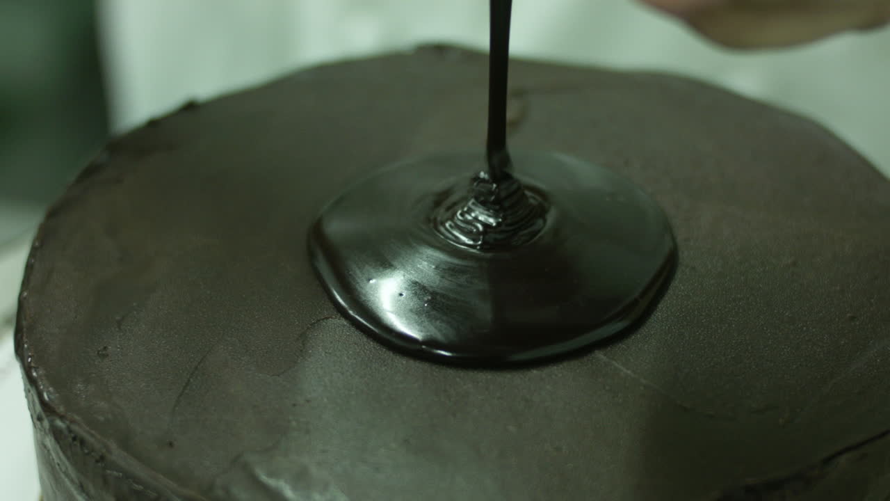 Versare sciroppo al cioccolato su una torta al cioccolato.