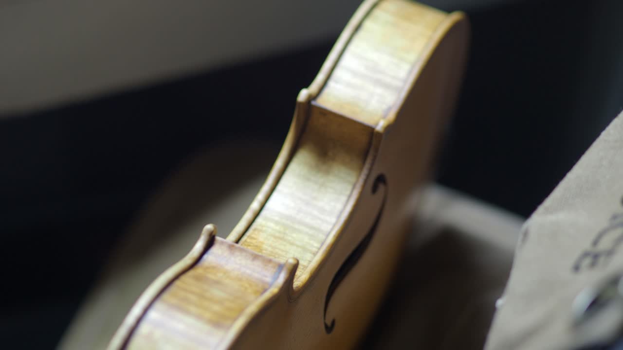 Expert Craftsman Applying Rich Amber Varnish to a Newly Crafted Violin Body in a Detailed Close Up Shot