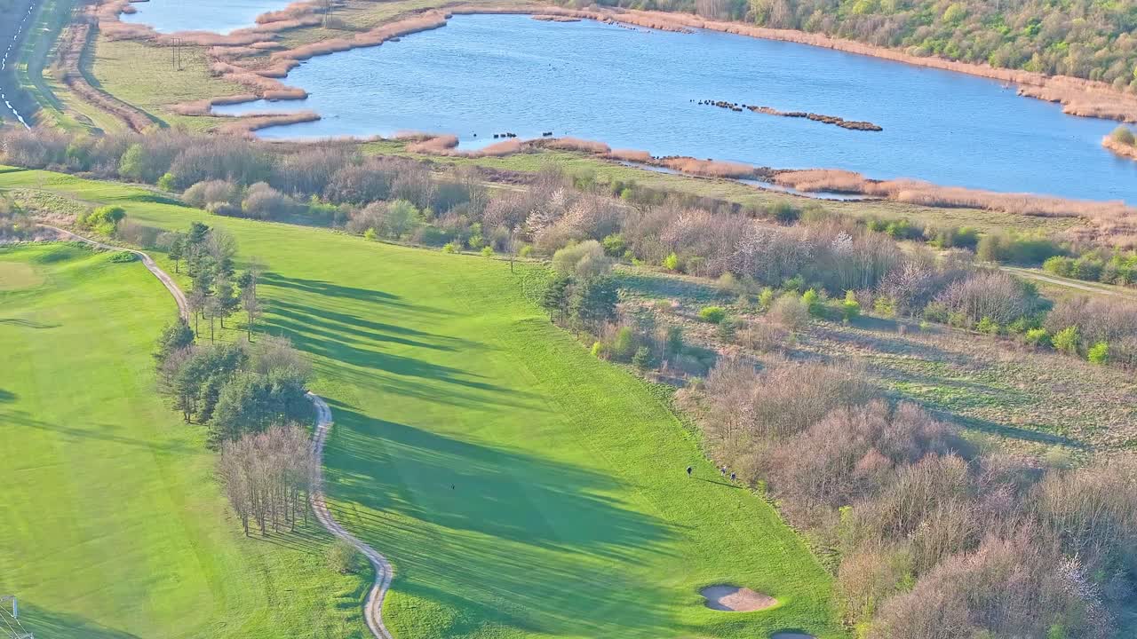 Aerial view of Waterfront Golf Club in Rotherham, South Yorkshire, UK, showcasing vibrant green fairways, shimmering lakes, in warm fall season