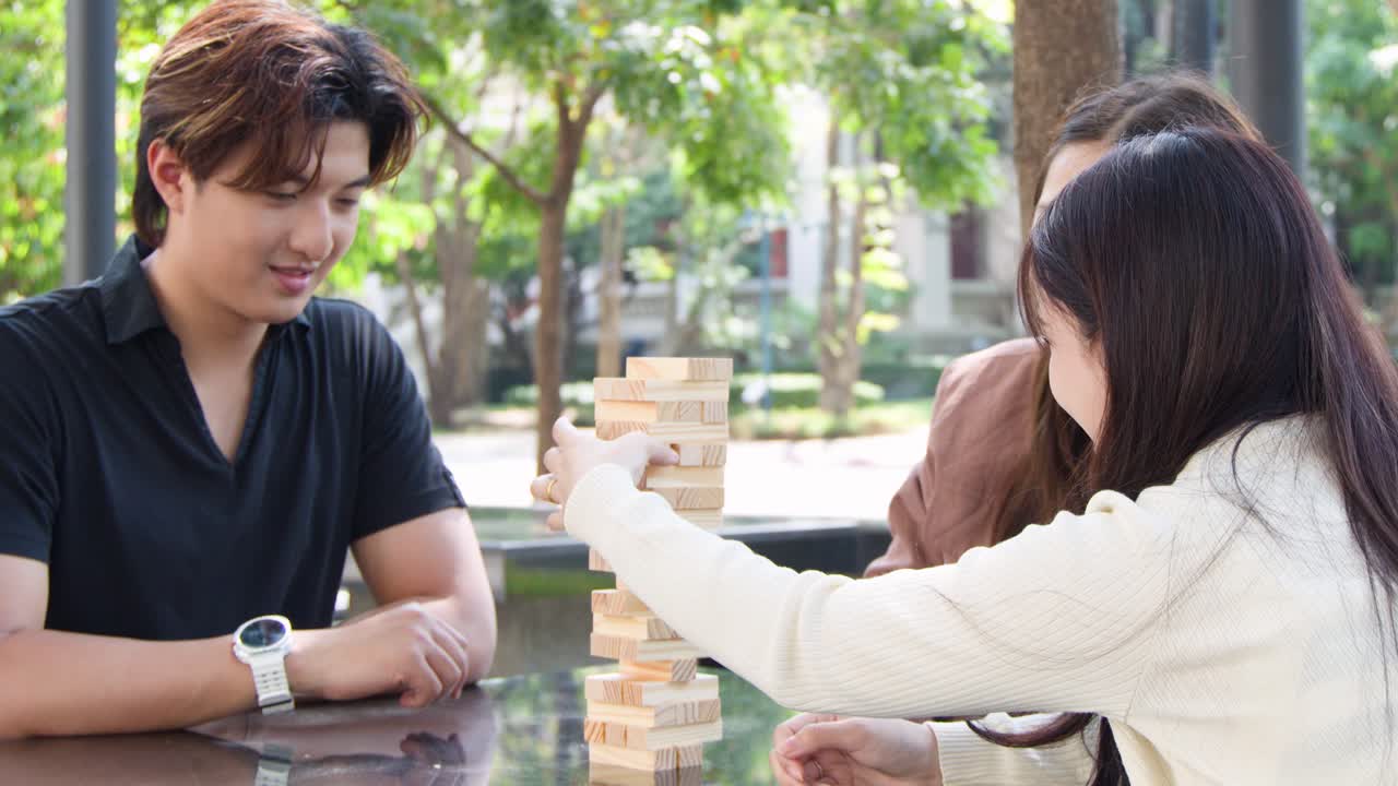 タイの屋外ゲーム中、木製のタワーが崩れて若い友人たちが笑っています。