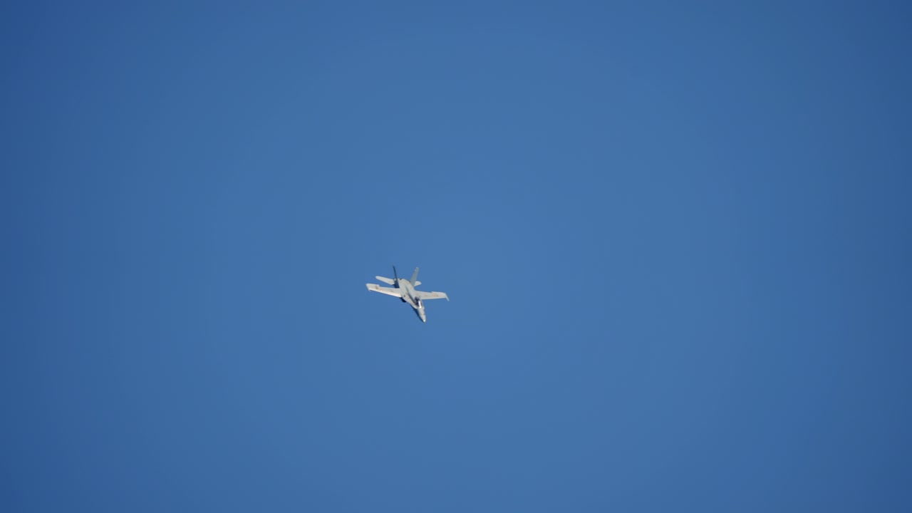 Stridsflygplan med dubbla stjärtfenor dyker genom blå himmel