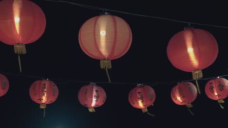 las linternas chinas cuelgan de cables contra el cielo nocturno oscuro