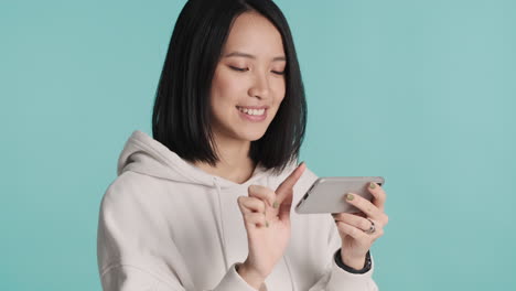 asian woman watching online video on smartphone and laughing.