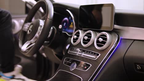 a man sits down in a сlean and luxurious interior of a brand new car, featuring modern amenities and advanced features.