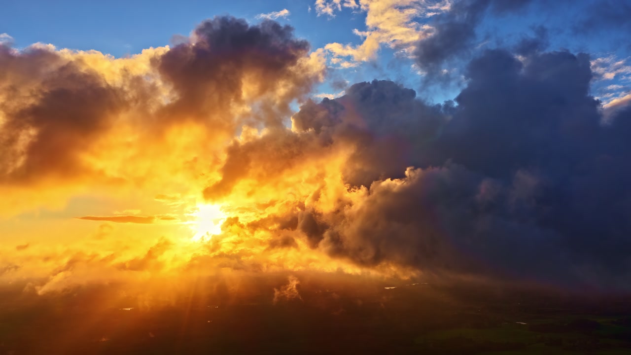 Dramatic golden sunset with sun rays breaking through the dark clouds