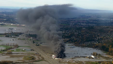 dark smoke rising from burning storage yard in british columbia, canada after rainstorm