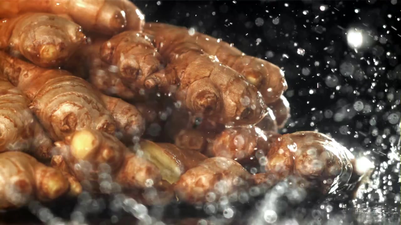Radici di zenzero fresco lavate con acqua al rallentatore.