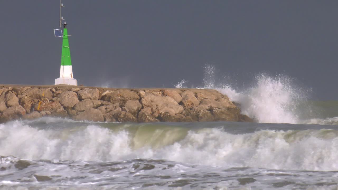 Harbor wall with powerful waves breaking into spray, slow motion