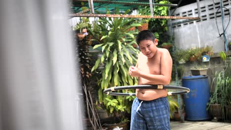 fat boy playing hula hoop at backyard, slow motion with belly moving.