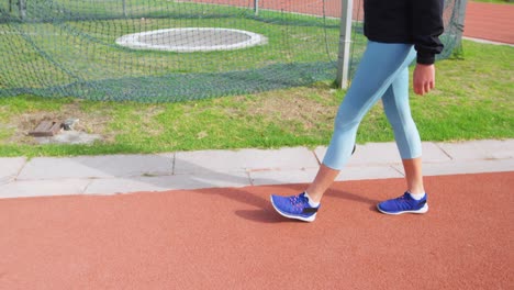 Vista-Lateral-De-Una-Atleta-Caucásica-Caminando-En-La-Pista-De-Carreras-En-El-Recinto-Deportivo-4k