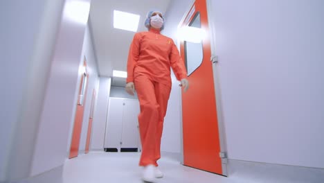 Trabajador-De-Una-Fábrica-Farmacéutica-Caminando-En-Un-Pasillo-De-Laboratorio-Estéril