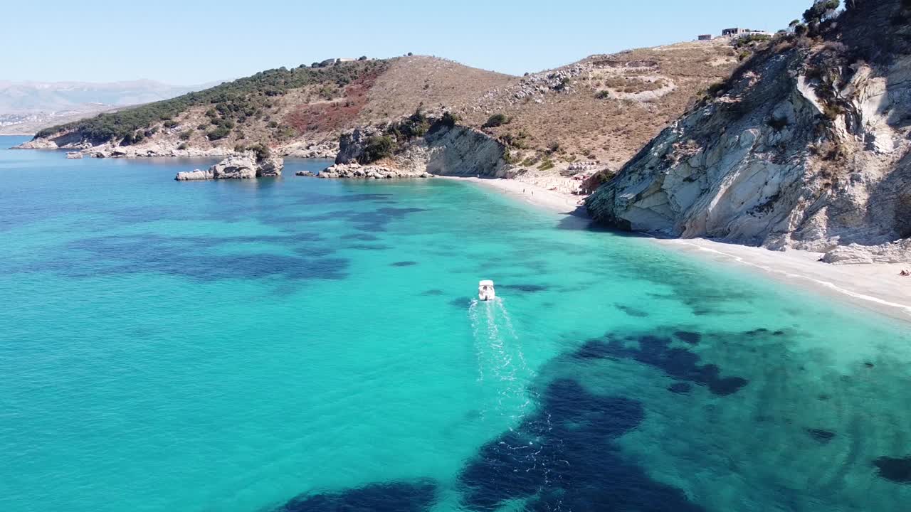 el barco navega sobre el azul claro del mar jónico para reflejar la playa en ksamil, albania - seguimiento de dolly aéreo