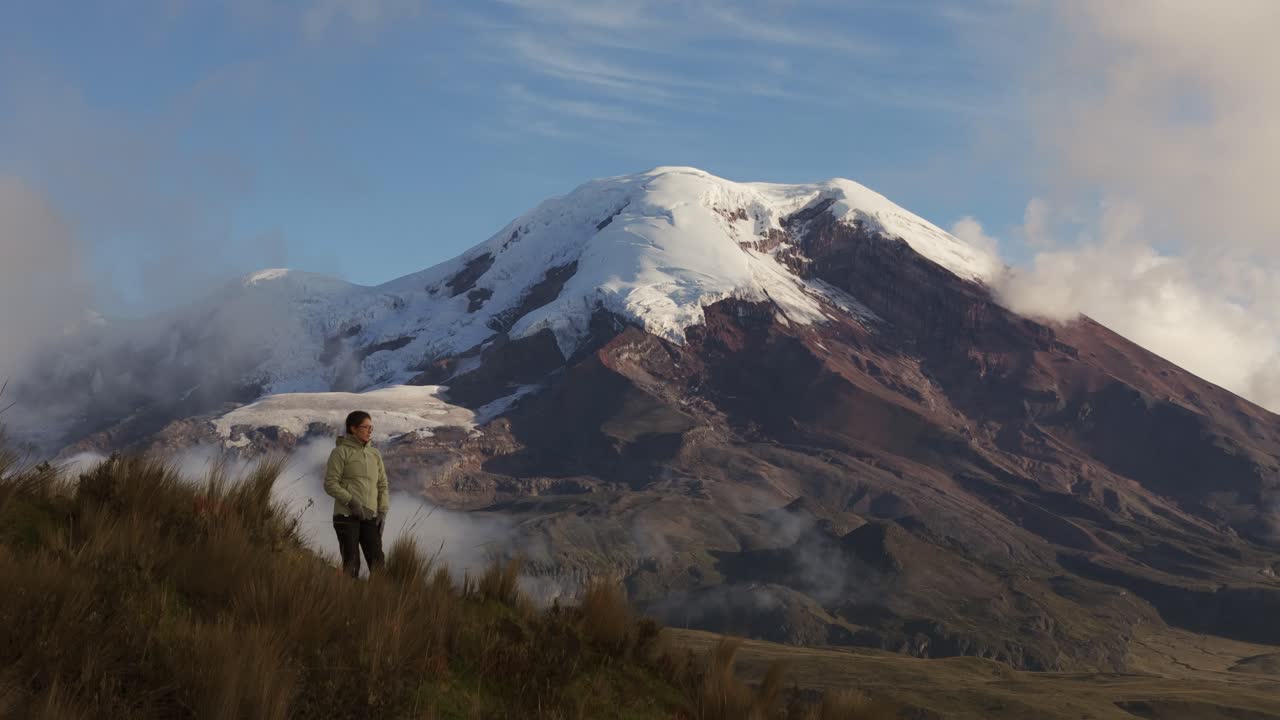 Woman walking alongside Chimborazo Volcano, Ecuador, with expansive mountainous terrain, ascend reveal