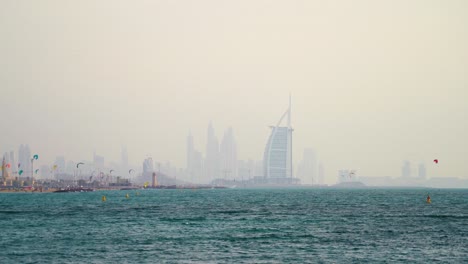 Playa-Escénica-Con-Hotel-De-Lujo-Burj-Al-Arab-En-Segundo-Plano-En-Dubai,-Emiratos-árabes-Unidos-Durante-La-Mañana-Brumosa