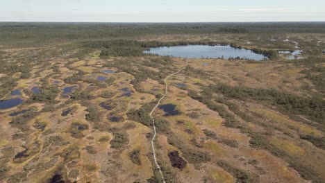 Vista-Aérea:-Un-Estrecho-Paseo-Marítimo-Conduce-A-Través-Del-Pantano-Del-Páramo-Norte-Hasta-Un-Pequeño-Lago