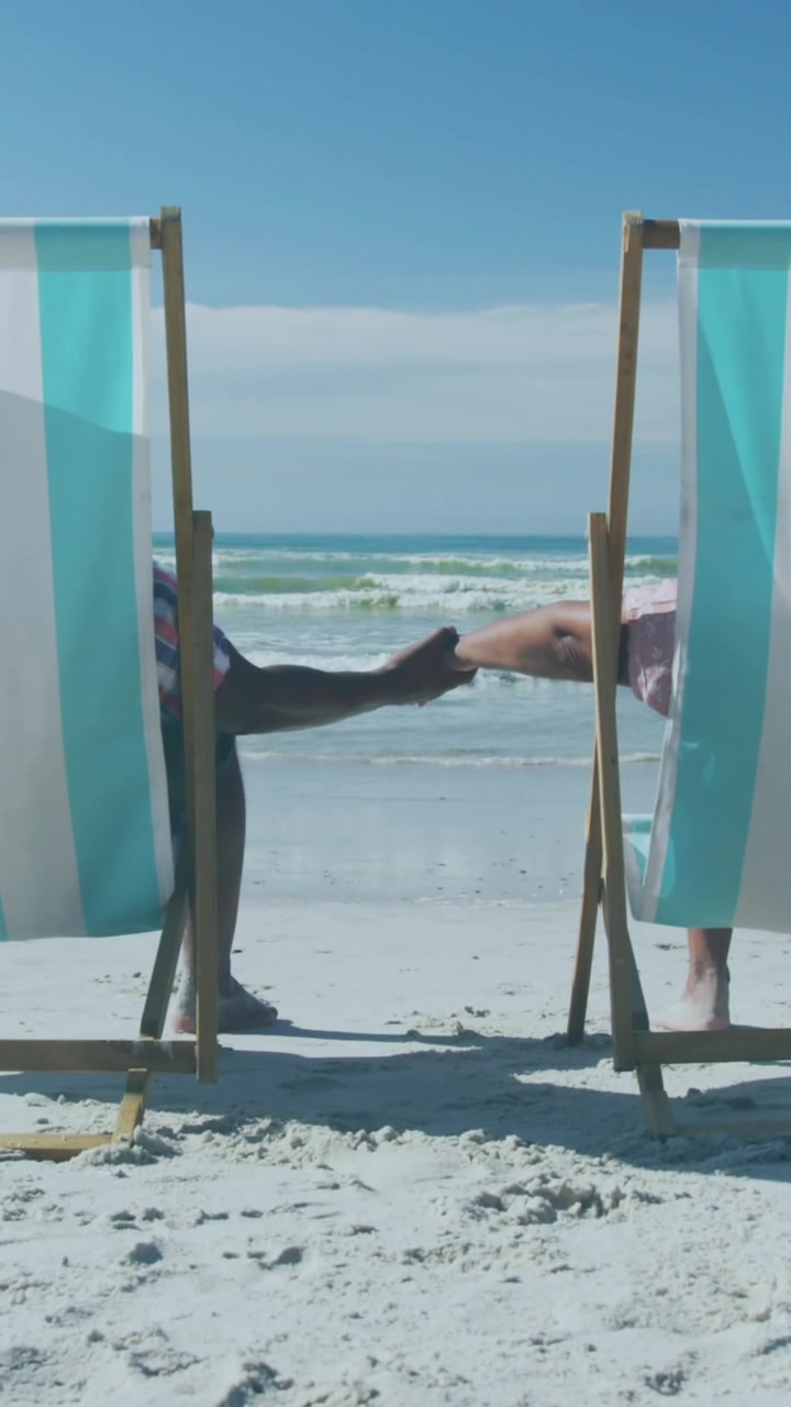 Animation of sun over senior african american couple lying on sunbeds on sunny beach