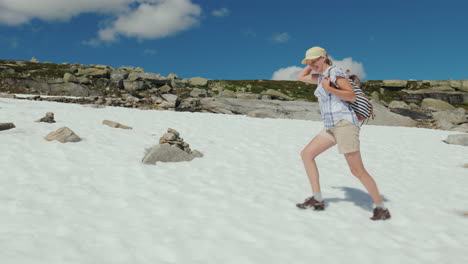 a woman is walking on the snow in the mountains outside it's a hot summer the snow has not melted ye