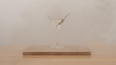 studio product shot of margarita and olive in clean glass on wooden table