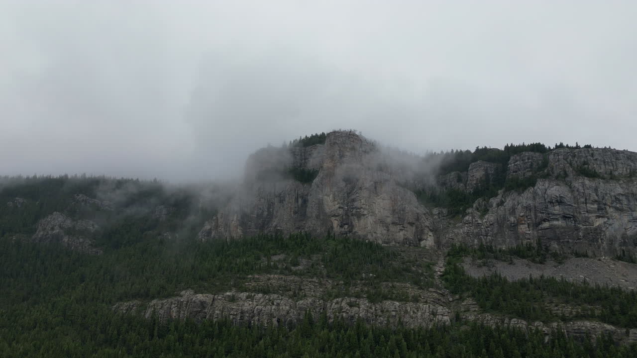 montaña oscura y brumosa envuelta por nubes y árboles